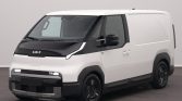 Front three-quarter view of a white cargo van with black hood and bumper, parked indoors.