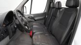 Interior of a vehicle showing three seats in a row with worn fabric on the driver's seat and a visible steering wheel and dashboard.