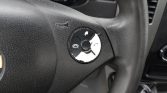 Round multifunction steering wheel control pad with phone and audio icons; outer ring shows peeling white cover and damage.
