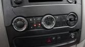 Car climate control panel with a left temperature dial, a central fan and mode dial, and warning icons on the buttons below the vents.