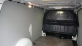 Empty cargo van interior with gray walls, wheel arches, and a back panel ready for loading