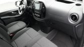Interior of a car showing the driver's area: steering wheel, center dashboard with touchscreen, and front seats in dark fabric.