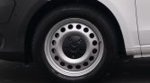 Steel wheel with circular holes and a Mercedes-Benz center cap on a light-colored van wheel well area; front driver's side tire visible