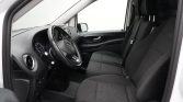 Black fabric front seats and steering wheel in a car cabin, view from open driver's door showing dashboard and door panel acabient details