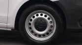 Close-up of a white van front wheel with a silver steel rim and a black center cap bearing the Mercedes logo.