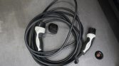 Coiled Mercedes‑Benz EV charging cable with two-tone handles on a carpeted surface