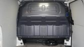 Rear cargo area of a van with a gray metal bulkhead panel and coiled cables on the floor.