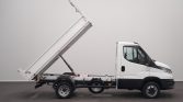 White dump truck with its cargo bed raised for unloading in a neutral setting on a paved surface