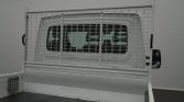 White truck cab visible behind a tall metal wire mesh partition in the truck bed