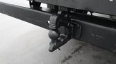 Close-up of a trailer hitch ball and mount on a black metal frame, ready for towing