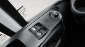 Close-up of a car's driver-side control panel: two power window buttons and a circular mirror adjustment knob.