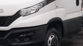 Front left side of a white cargo van, showing headlight, grille, and front wheel.
