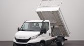 Front three-quarter view of a white Iveco dump truck with its bed raised for dumping, hydraulic lift visible