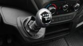 Manual gear shift knob with pattern R 1 3 5 / 2 4 6, leather boot, climate controls visible in the background