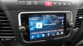 Car dashboard with a centered touchscreen displaying 'Toestel aansluiten' and surrounding climate and control buttons on a dark panel.
