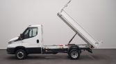 White dump truck with its cargo bed raised to unload material (side view) for dumping action.