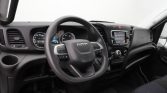 Interior of a vehicle cockpit focusing on a steering wheel with Iveco branding and dashboard controls behind it
