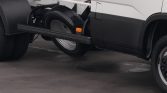 Side view of a truck chassis with a long black side rail and spare tire mounted beneath the cab.