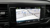 In-car GPS navigation screen showing a map with blue POI icons and a roundabout ahead.