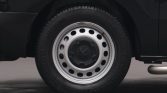 Close-up of a silver steel wheel with circular holes and a black center cap on a dark vehicle, showing the tire tread around it.