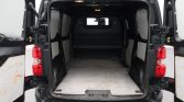 Open cargo van with rear doors swung wide, showing a wide, empty loading area with a grey floor mat and side panels ready for gear or deliveries.