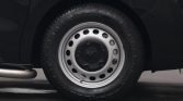 Close-up of a car wheel: silver steel rim with a black center cap on a dark vehicle.
