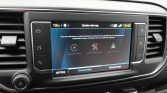 Center-mounted car infotainment touchscreen showing connectivity options (Apple CarPlay, Connected‑apps, Android Auto) with surrounding climate controls and side buttons.