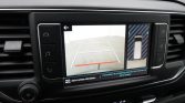Car infotainment screen showing a rearview camera with parking guide lines and a top-down car diagram on the right side.